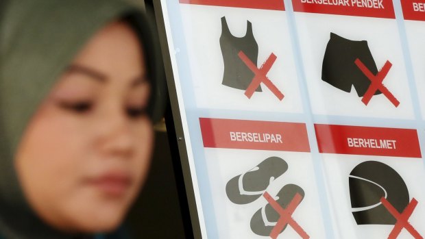 A woman walks past a dress code sign in Kuala Lumpur. Women in Malaysia have been denied entry to government buildings on the grounds their skirts were too revealing, fanning fears of growing conservatism in a country with large non-Muslim minorities. 