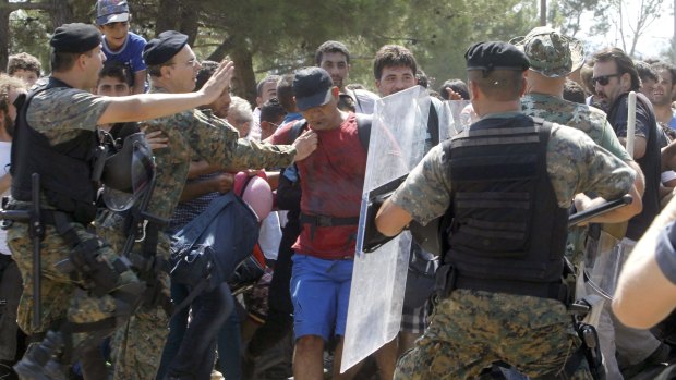 Police try stop a group of migrants as they attempt to enter Macedonia from Greece.