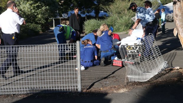 Paramedics treat a patient after a car smashed through the Wollongong Public School fence.