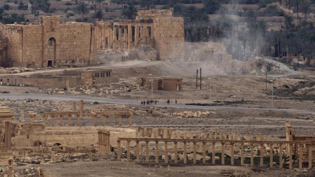 Russian soldiers on a road as smoke rises from a controlled land mine detonation by Russian experts inside the ancient town of Palmyra in Syria earlier this month. 