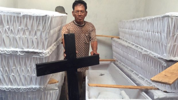 Undertaker Suhendro Putro's assistant, Sulamin, with the extra coffins ordered for the executions.