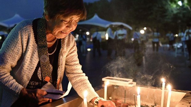 A woman lights a candle as she prays for the atomic bomb victims in front of the cenotaph at the Hiroshima Peace Memorial Park on Saturday August 6.
