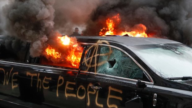 A parked limousine burns during a demonstration after the inauguration of President Donald Trump.
