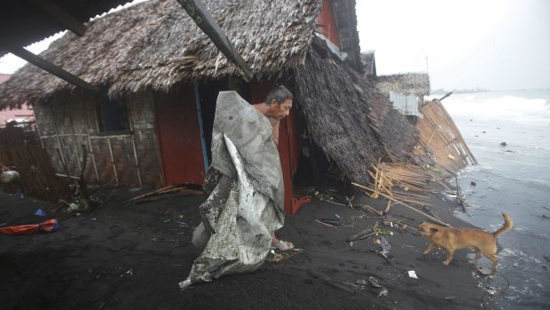 A Filipino man carries a dirty plastic sheet from his house after strong waves from Typhoon Hagupit battered a coastal village in Legazpi, Albay province. 