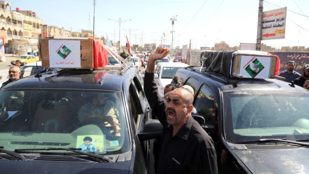 Mourners carry the Iraqi flag-draped coffins of two protesters killed in the clashes.