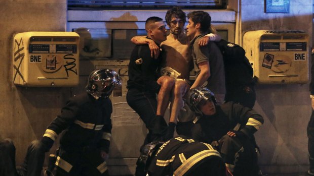 French fire brigade members aid an injured individual near the Bataclan following fatal shootings in Paris.