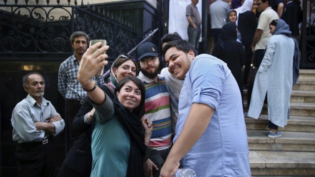Friends take a selfie while lining up outside a polling station to vote for the presidential and municipal councils election in Iran.