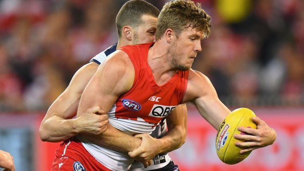 Injury cloud: Luke Parker of the Swans handballs whilst being tackled by Sam Menegola.