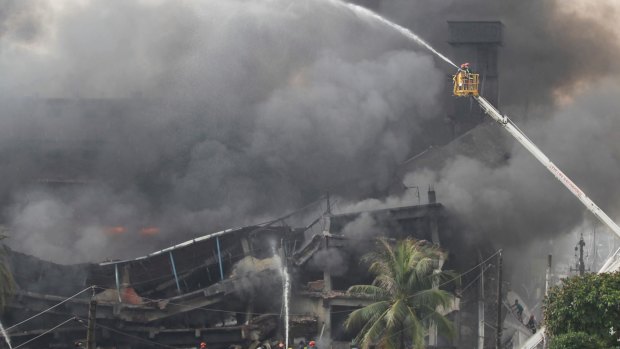 Firefighters on a ladder work to put out the fire at a packaging factory in Tongi industry area outside Dhaka.