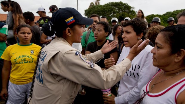 A police officer talks to an angry crowd during a protest for food at the Catia neighbourhood in Caracas, Venezuela, last year.