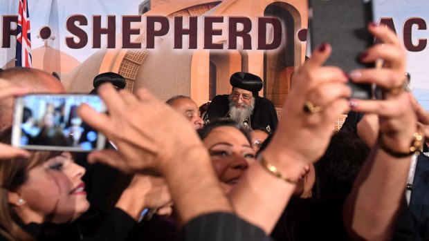 Attendees are seen taking photographs of Pope Tawadros II.