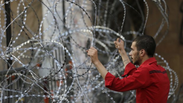 A Lebanese activist holds barbed wire barriers in front of the government house during a protest against the rubbish crisis and government corruption in Beirut this week. 