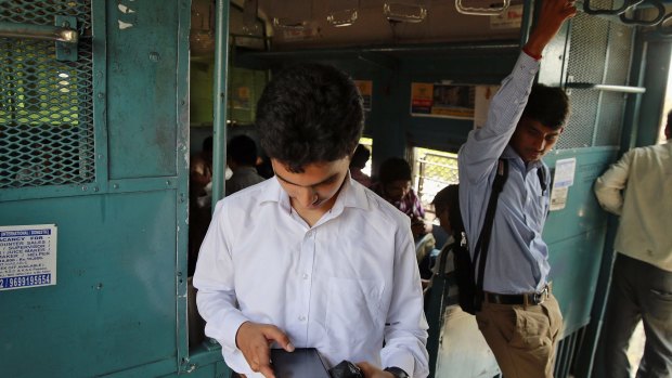A man checks the internet on his smartphone during a train ride in Mumbai.