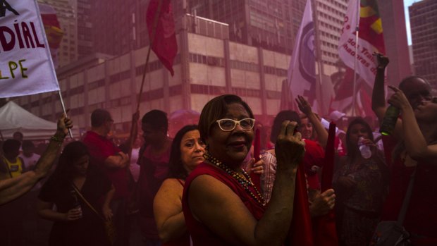 Supporters of Dilma Rousseff stand in red smoke during a pro-government demonstration in Rio de Janeiro on Thursday.