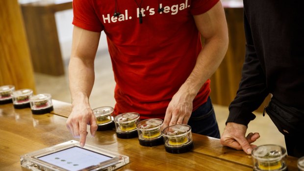 An employee wears shirt reading "Heal. It's Legal" while helping a customer select marijuana strains at the MedMen dispensary in West Hollywood.