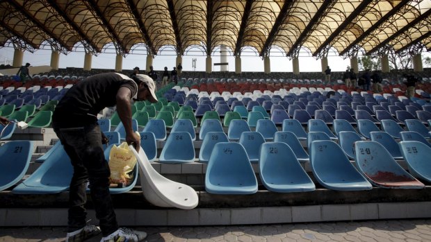 A worker repairs seats in an enclosure at the Gaddafi Stadium.