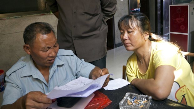 Farmer Li Laiyin (left), 64, and his neighbours look through a list of local residents with elevated levels of lead in their blood, in Dapu, Hunan province.