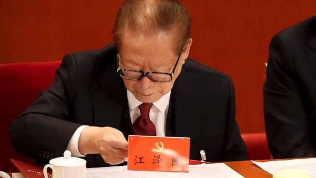 Former Chinese President Jiang Zemin examines his nametag during the opening session of the congress.
