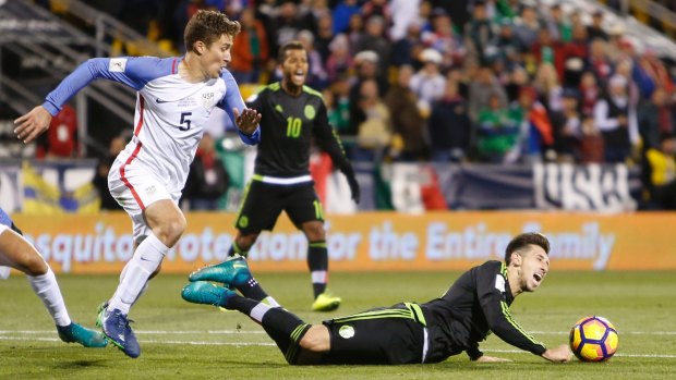Mexico's Hector Herrera goes to ground as United States' Matt Besler attacks inthe World Cup qualifying match.