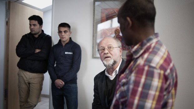 The Reverend Peter Brummer, centre right, of the St Joseph Roman Catholic church talks with an asylum seeker as two others - Abdullah Zadran, left, and Ali - stand by.