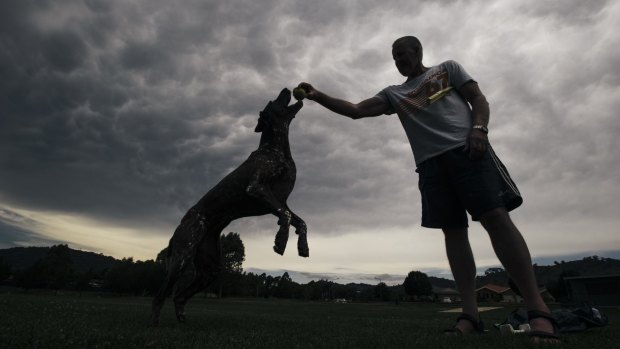 Banks resident Ian Foster and his dog, Jess, underneath mammatus clouds in Tuggeranong on Tuesday afternoon.