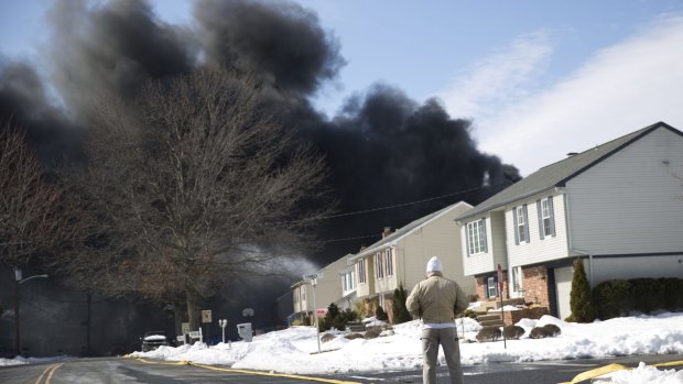 A man looks at heavy black smoke over  Pennsauken, New Jersey. 