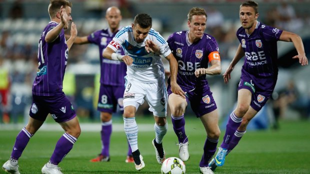 Kosta Barbarouses of Melbourne Victory tries to break through a cordon of Perth Glory defenders.