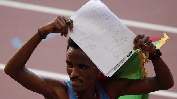 Ghirmay Ghebreslassie of Eritrea holds up a handwritten message after winning the men's marathon.