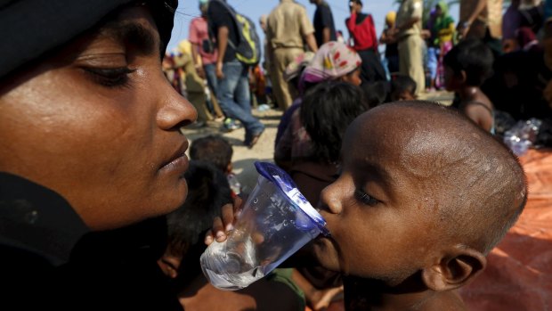 A Rohingya migrant mother watches as her child drinks water after they arrived in Indonesia by boat.