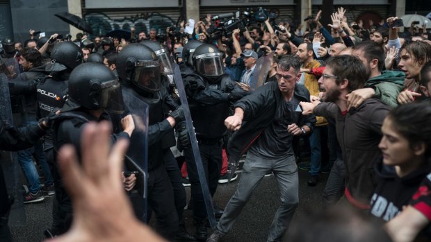 People confront Spanish riot police near a voting site at a school assigned to be a polling station.