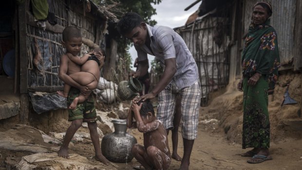 A Rohingya man bathes his child at the Kutupalong Refugee Camp in Teknaaf, Bangladesh.