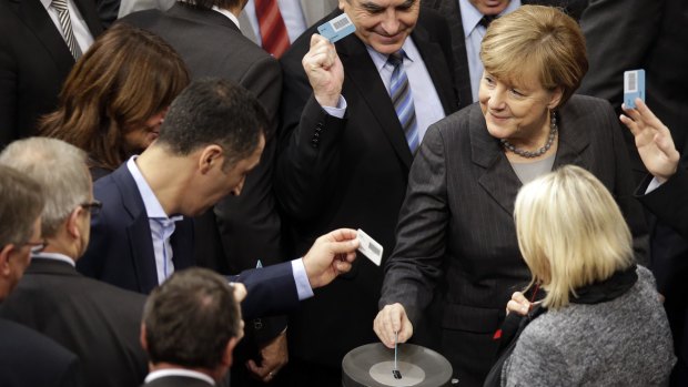 German Chancellor Angela Merkel, right, casts her vote at the German parliament  in Berlin on Friday.
