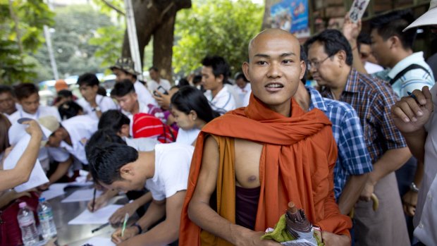 A Buddhist monk walks as others sign an attendance register during a rally by Myanmar nationalist groups on Sunday in support of preserving a constitutional clause barring Aung San Suu Kyi from becoming president.