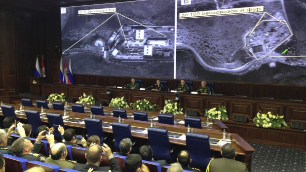 Russian military officials speak to the media in front of aerial images they say are oil trucks near Turkey's border with Syria at a briefing in Moscow on Wednesday.