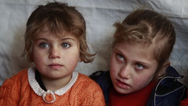 Syrian refugee Eman al-Aqraa, 8, right, and her sister Fatima, 4, listen to their teacher inside a tent that has been turned into a makeshift school, at a Syrian refugee camp in Qab Elias, a village in the Bekaa valley, Lebanon. 