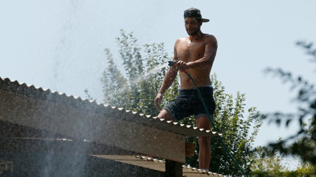 Wandin resident Ricky Booth hoses down his friend's roof.