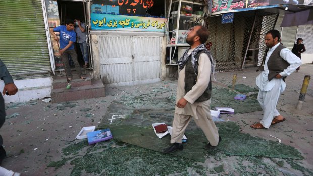 Afghan men walk over broken glass after the blast.