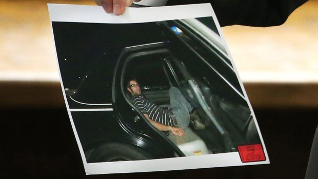 Erath County District Attorney Alan Nash carries a photo of former Marine Cpl. Eddie Ray Routh handcuffed in the back of a Lancaster Police car the night of his arrest.