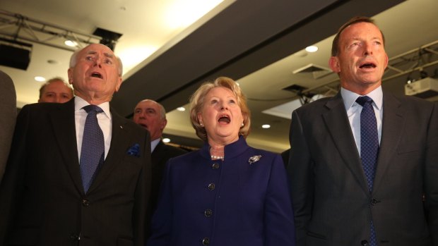 John Howard, Janette Howard and Tony Abbott sing the national anthem.