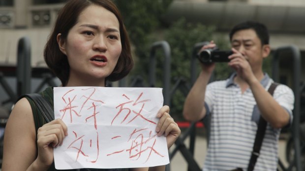 A man films Li Wenzu, left, wife of imprisoned lawyer Wang Quanzhang, holding a paper that reads "Release Liu Ermin"  outside the Tianjin court on Monday.  Liu Ermin is a wife of one of the activists, who was arrested on Sunday, July 31.  