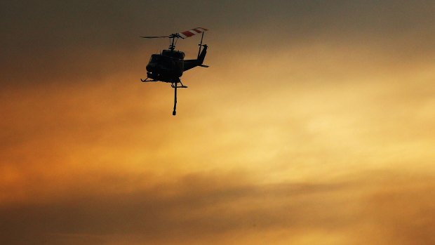 Helicopters carry water as part of reduction drops for the bushfire in Warrimoo.