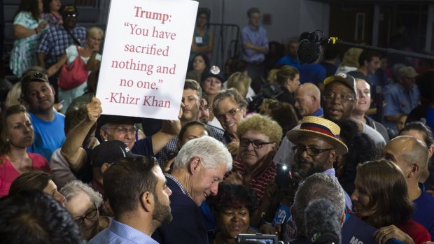 A man holds a sign criticising Donald Trump as former president Bill Clinton greets Democratic supporters in Youngstown, Ohio.