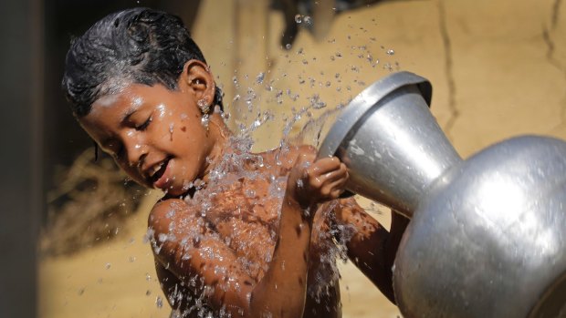 A Rohingya Muslim girl pours water on herself as she bathes outside her tent in Kutupalong Refugee camp in Bangladesh on Monday.