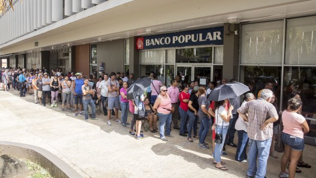 People stand in line to withdraw cash from an automatic teller machine after Hurricane Maria heavily damaged the government-run electricity system in the Miramar neighborhood of San Juan.