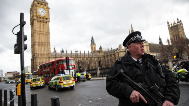 An armed police officer stands guard near Westminster Bridge.