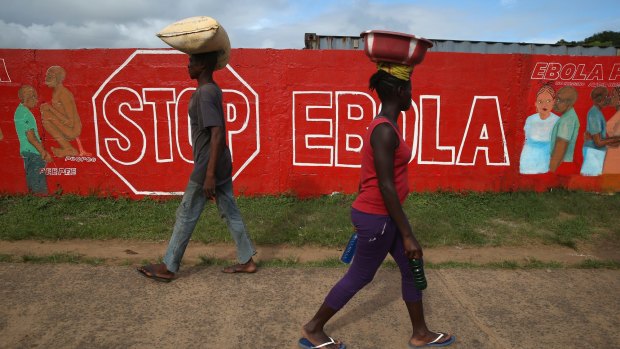 People pass an Ebola awareness mural in Monrovia, Liberia. More than 3,200 people have died in West Africa due to the epidemic.