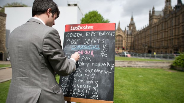 A bookmaker writes the latest odds on the result of the upcoming UK general election outside the Houses of Parliament in central London on May 6, 2015. 
