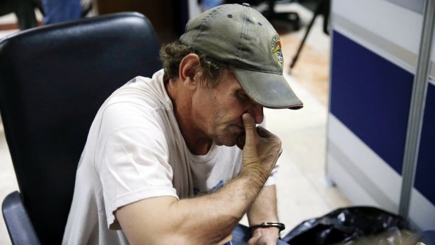 David Timothy Deakin is handcuffed to a chair at the National Bureau of Investigation in Manila, Philippines, on April 21.  Authorities say his arrest has resulted in one of the largest seizures of illicit digital content in the country's history.  