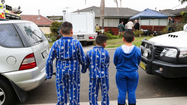 Children watch as police search a house on Pollock Street, Georges Hall. 