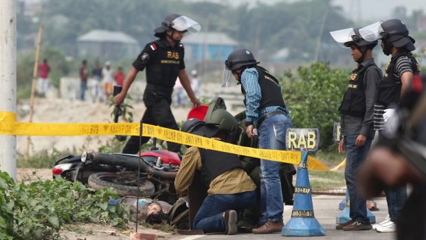 Bangladesh Rapid Action Battalion (RAB) personnel and bomb experts inspect the body of a man beside a RAB checkpoint in Khilgaon, Dhaka, Bangladesh.